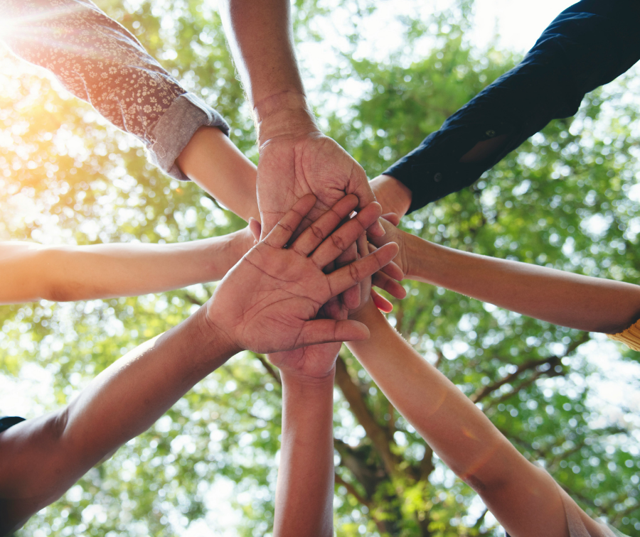 Mehrere Hände liegen übereinander als Symbol für Gemeinschaft, Zusammenhalt und ehrenamtliches Engagement.